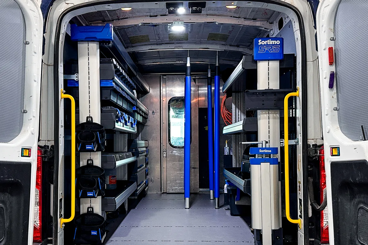 Ford Transit cargo van upfitted with Sortimo shelving, LED lighting, yellow grab handles, and protective flooring
