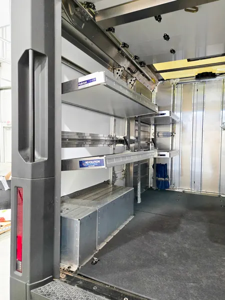 Side view along box truck shelving with wall-mounted bins and a rear step