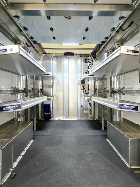 Shelving and lower compartments inside a box truck body, looking toward the front bulkhead