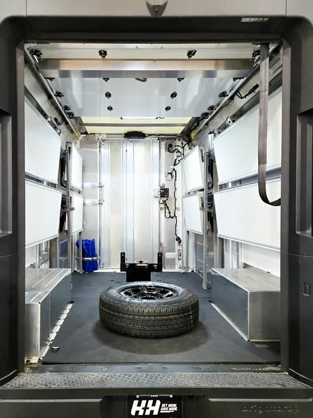 Box truck cargo area with shelving both sides and a spare tire mounted in the center of the floor