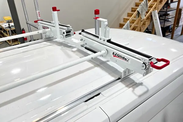 Close-up of an EZGlide drop-down ladder rack mechanism mounted on a white van roof