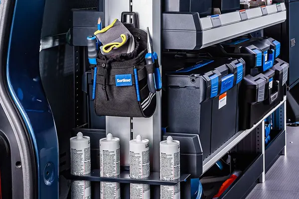 Close-up of Sortimo shelving and blue parts cases behind the side door of a blue van