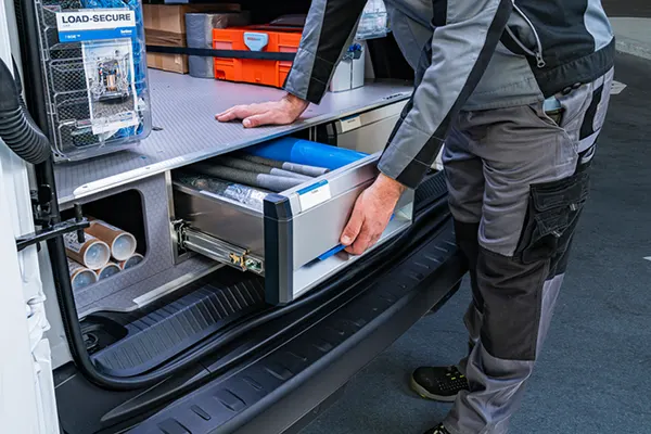 Worker pulling out a Sortimo load-secure drawer unit from the rear of a van