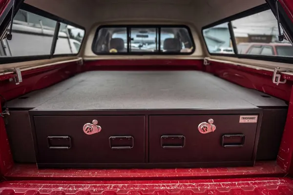 Carpeted two-drawer TruckVault in a red pickup bed under a truck cap