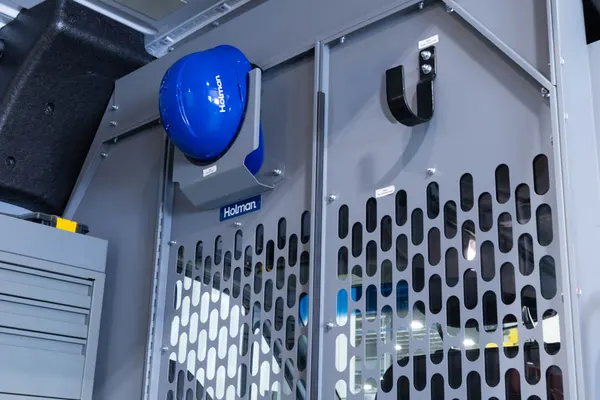 Perforated steel Holman partition with a hard-hat holder and hook, seen from the cargo side
