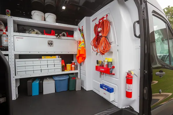 Holman steel bulkhead behind the driver seat, with shelving, drawers, and cord hooks along the van wall