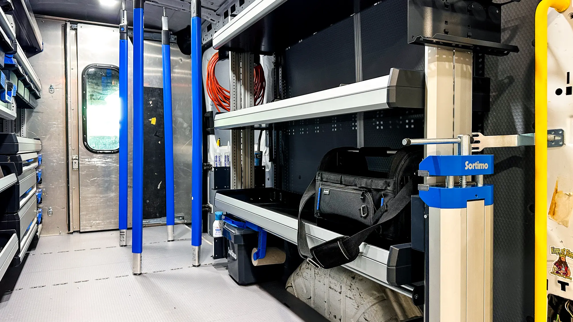 Upfitted van interior lit by overhead LED cargo lighting above Sortimo shelving