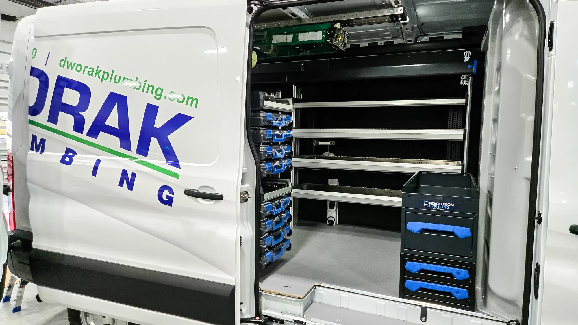 Dworak Plumbing work van with its side door open, showing Sortimo shelving, parts cases, and a Revolution drawer unit