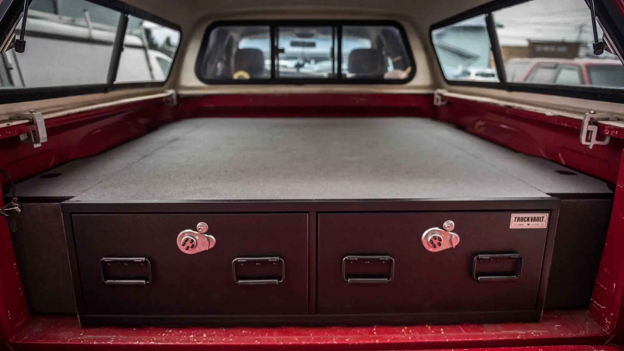 Pickup bed under a cap fitted with a two-drawer TruckVault storage system