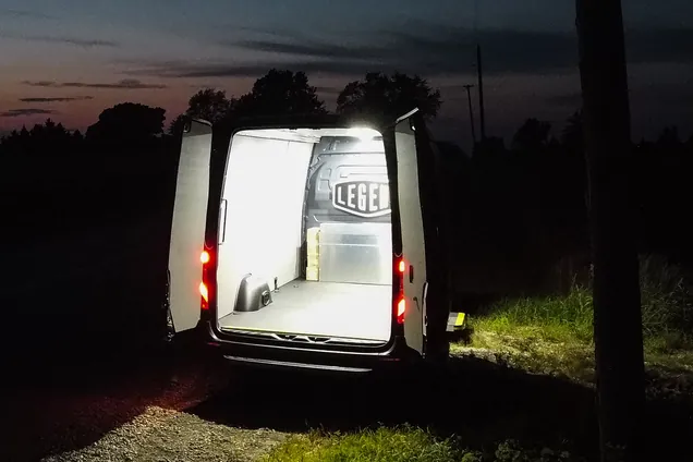 Work van at dusk with its rear doors open and the upfitted cargo area lit by LED lighting