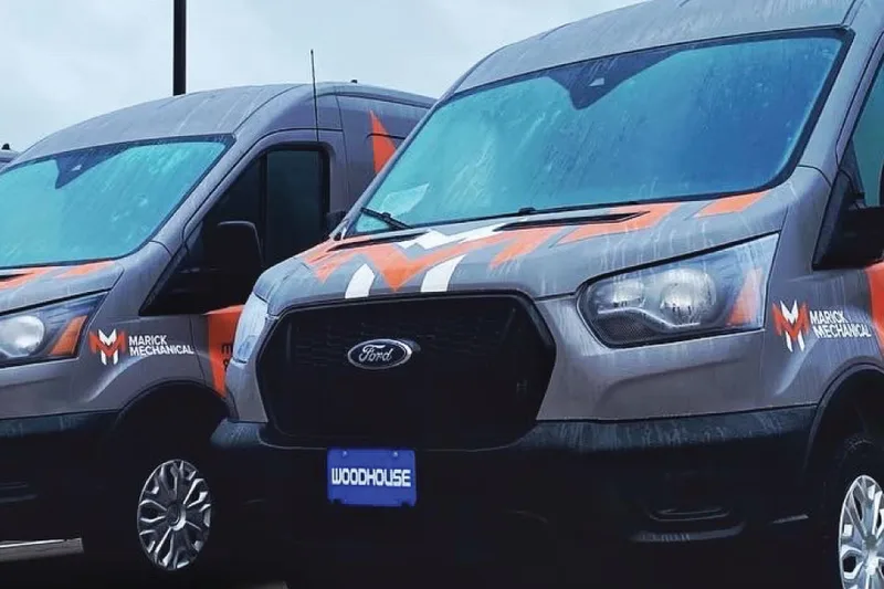 A row of matching wrapped fleet vans upfitted to one standard spec