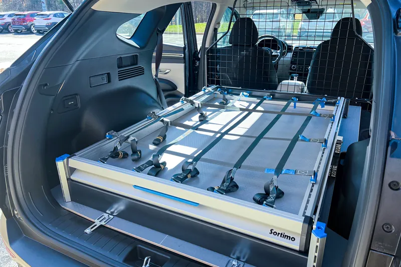 SUV cargo area with a mesh cargo barrier behind the rear seats and a Sortimo slide-out tray