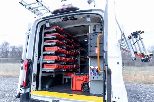 Upfitted work van with rear doors open showing drawers and rack storage