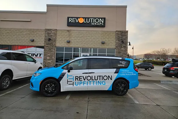 Revolution Upfitting branded minivan parked outside the shop